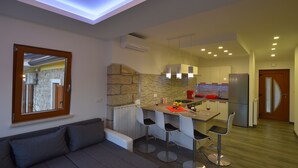 A modern kitchen with a stone accent wall, a dining area with bar stools, and a built-in oven.