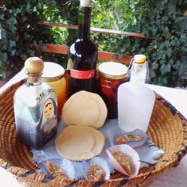 Una bandeja de mimbre con varias botellas, frascos y tazas de pastelería.