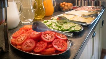 Un bufé con rodajas de tomate, pepino y otras comidas.