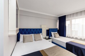 A hotel room with two beds, a nightstand, a lamp, and a window with curtains. - Sirkeci Family Hotel (Istanbul)
