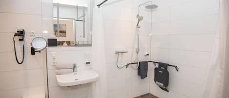 Un baño moderno con ducha, lavamanos y espejo.