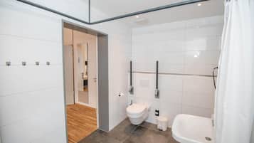 A modern bathroom with a toilet, bidet, and bathtub.