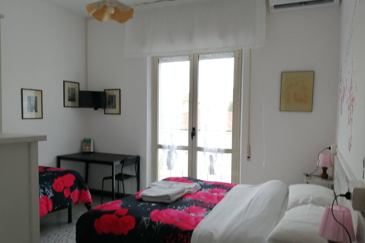Une chambre à coucher avec un lit, un bureau et une chaise. Il y a une fenêtre donnant sur l’extérieur.