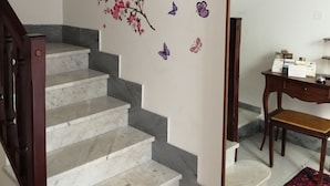 Eine Treppe mit Marmorstufen, eine Wand mit floralen Verzierungen und einem gerahmten Bild sowie ein Schreibtisch mit Stuhl und einem roten Teppich.