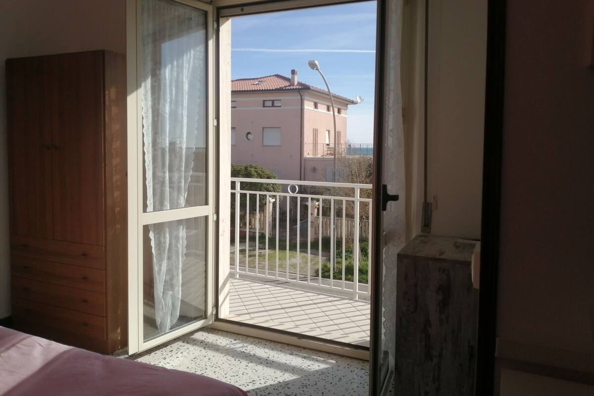 Une pièce dotée d’une porte-fenêtre coulissante donnant sur un balcon agrémenté d’une rambarde en métal.