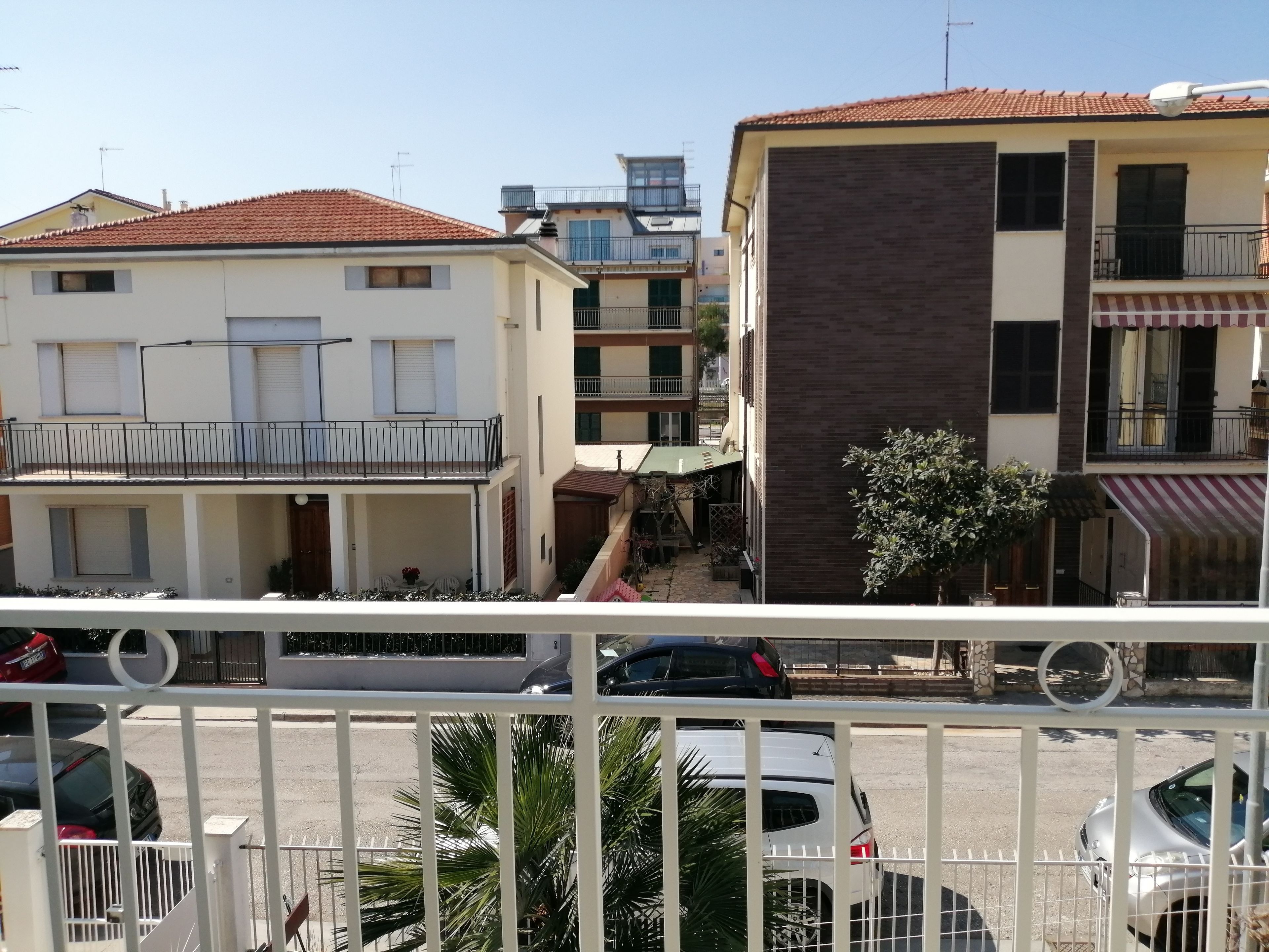 A residential area with multi-story buildings, balconies, and parked cars.