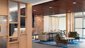 A modern interior with a stone wall, wooden ceiling, and a dining area with chairs and a table. - Fairfield Inn & Suites by Marriott Denver Tech Center North (Denver)