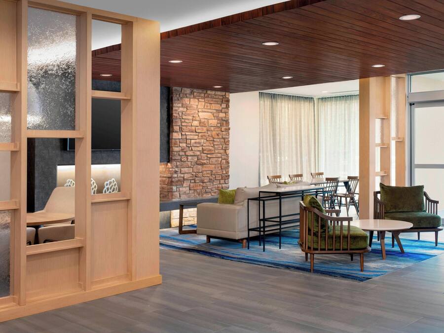 A modern interior with a stone wall, wooden ceiling, and a dining area with chairs and a table.