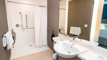 Ein modernes Badezimmer mit begehbarer Dusche, zwei Waschbecken, einem großen Spiegel und einem Handtuchhalter.