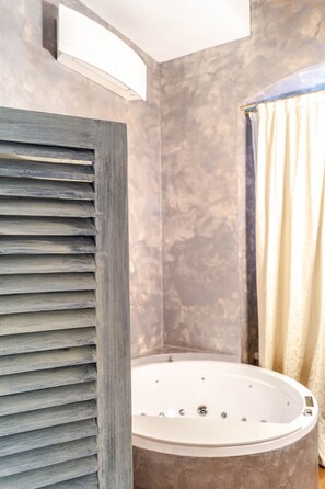 A modern bathroom with a large bathtub, a wooden slatted shower enclosure, and a textured wall. - Ilsanleonardo - Suites (Bergamo)