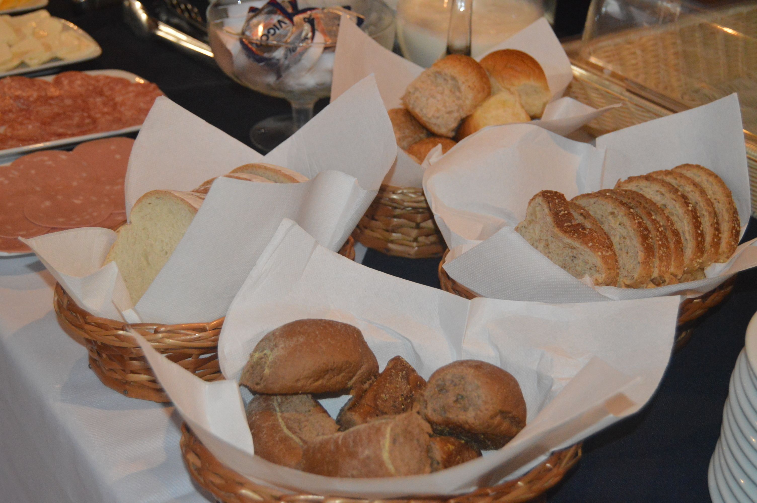A table with various types of bread and pastries in baskets.