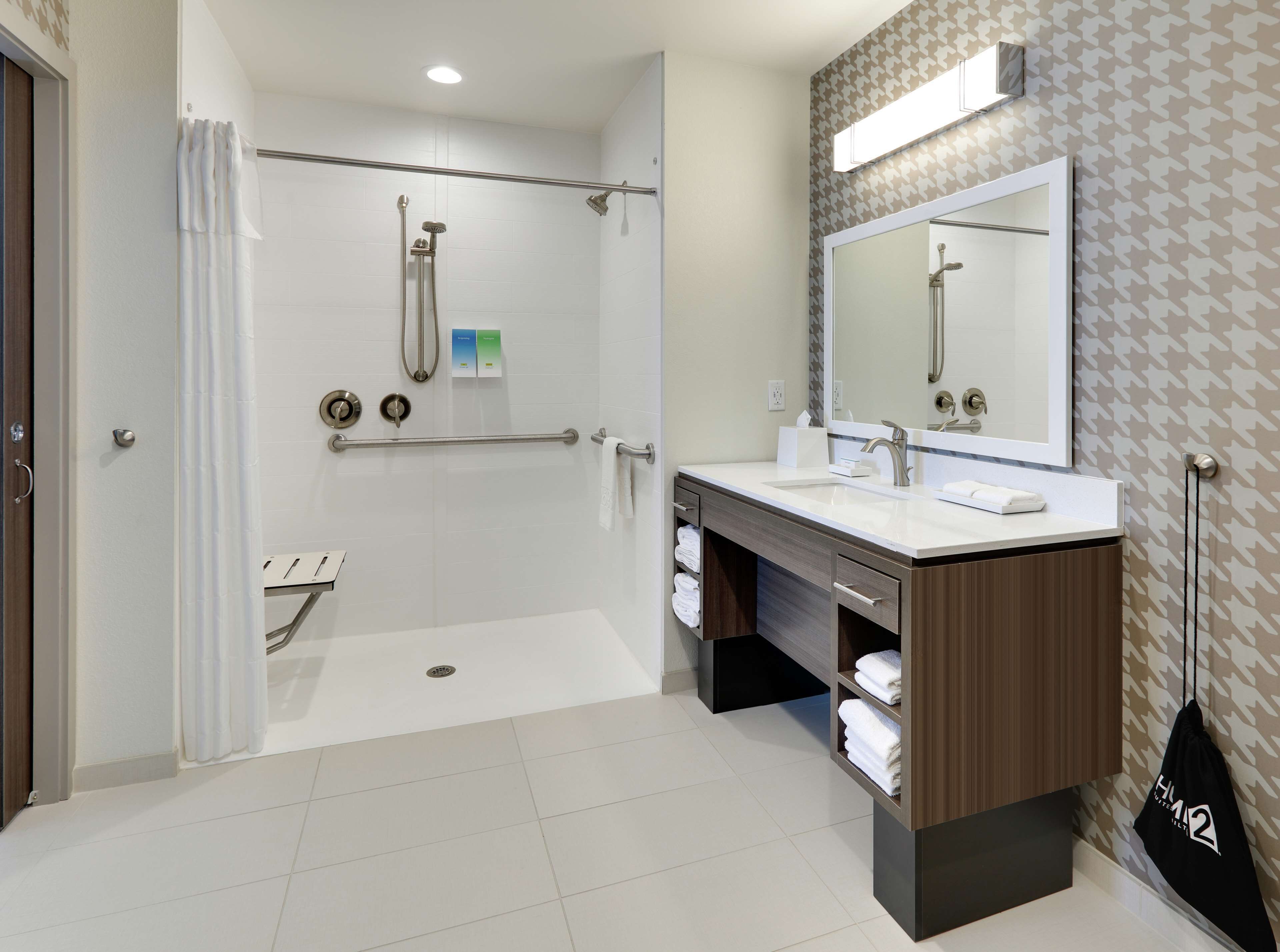 A modern bathroom with a walk-in shower, a vanity with a mirror, and a towel rack.