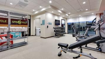 A gym with exercise equipment, a treadmill, and a wall-mounted TV.