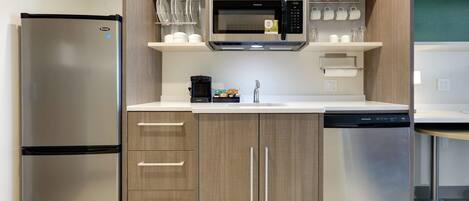 A compact kitchen with a stainless steel refrigerator, a microwave, and a dishwasher.