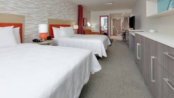 A hotel room with two beds, a desk, a TV, and a minibar.