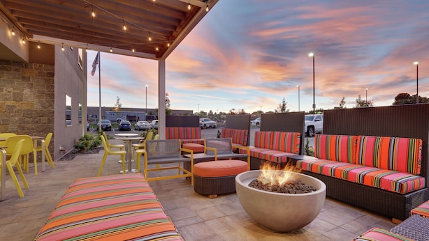 An outdoor patio with seating, a fire pit, and a view of the parking lot.
