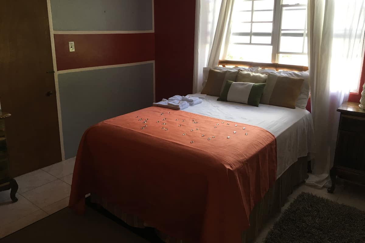 A bedroom with a bed, pillows, and a window with curtains.