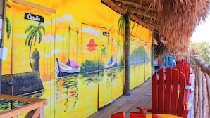 A vibrant mural with a sunset scene, including palm trees and boats, on a building's exterior wall.