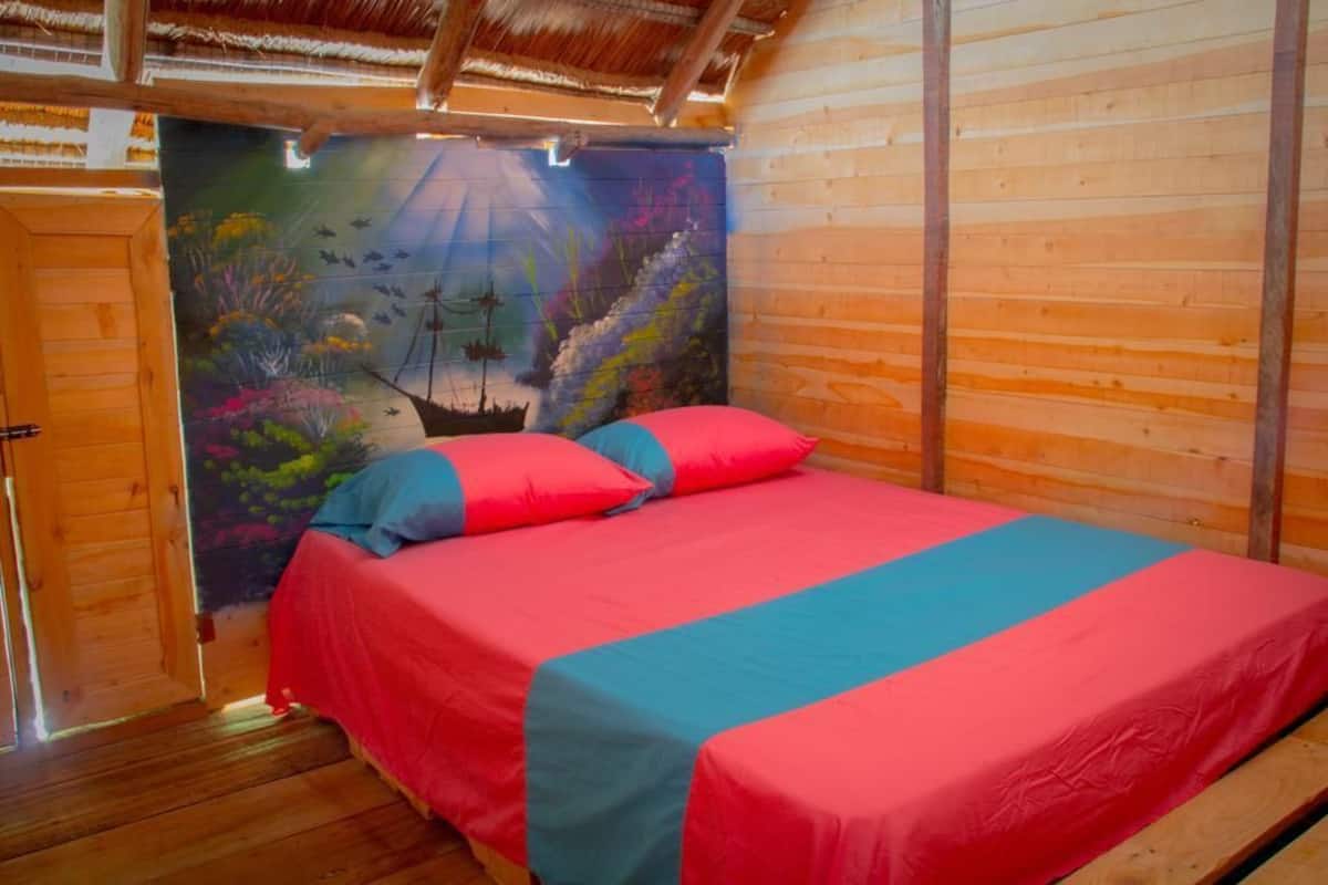 Une pièce de style cabane en bois, avec un lit, une fresque murale et une porte en bois.