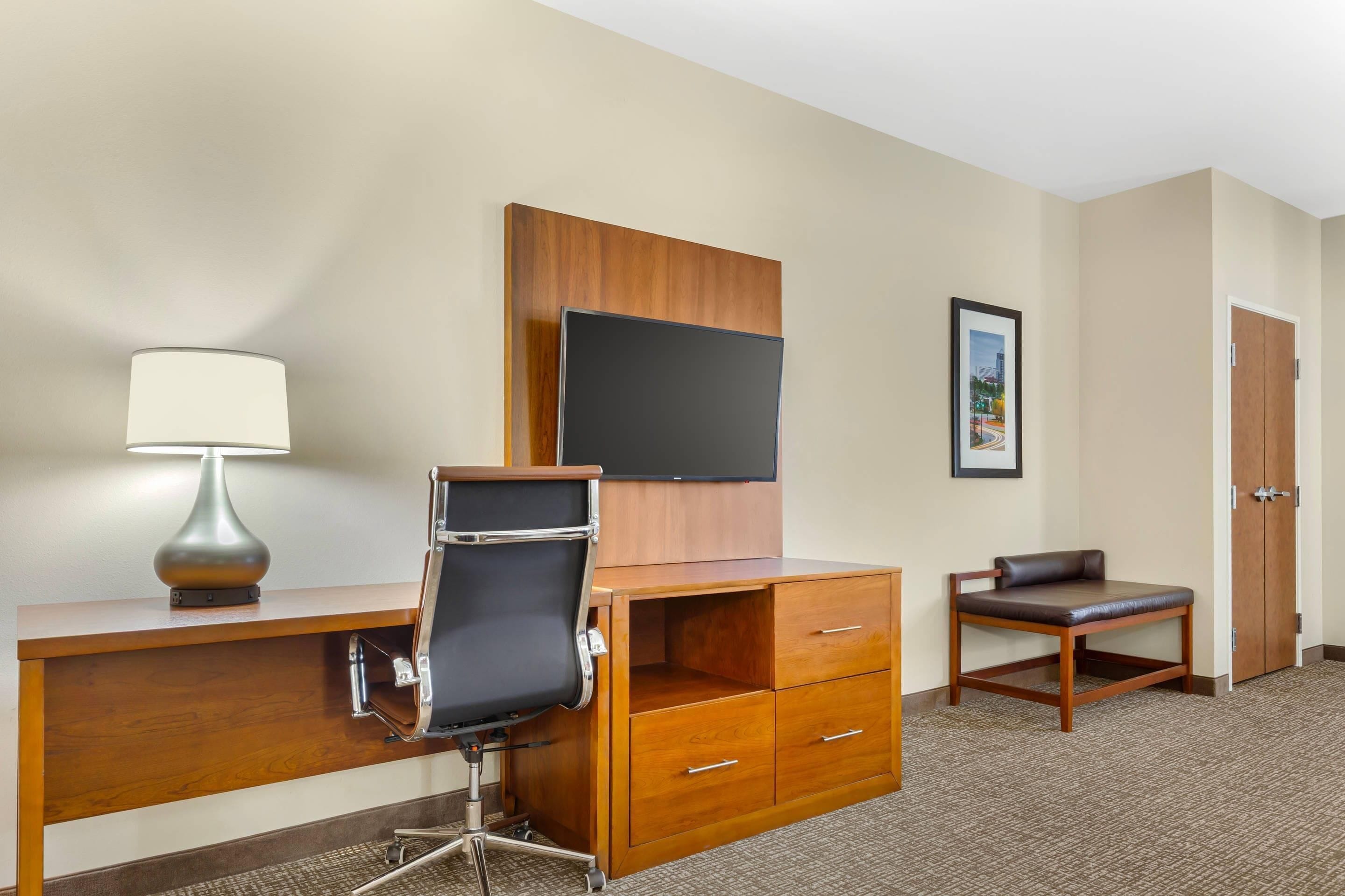 Une chambre d’hôtel équipée d’un bureau, d’une chaise, d’une télévision et d’un tableau encadré au mur.