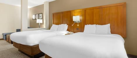Habitación de hotel con dos camas, una mesita de noche con lámpara, un teléfono y una lámpara de pared.