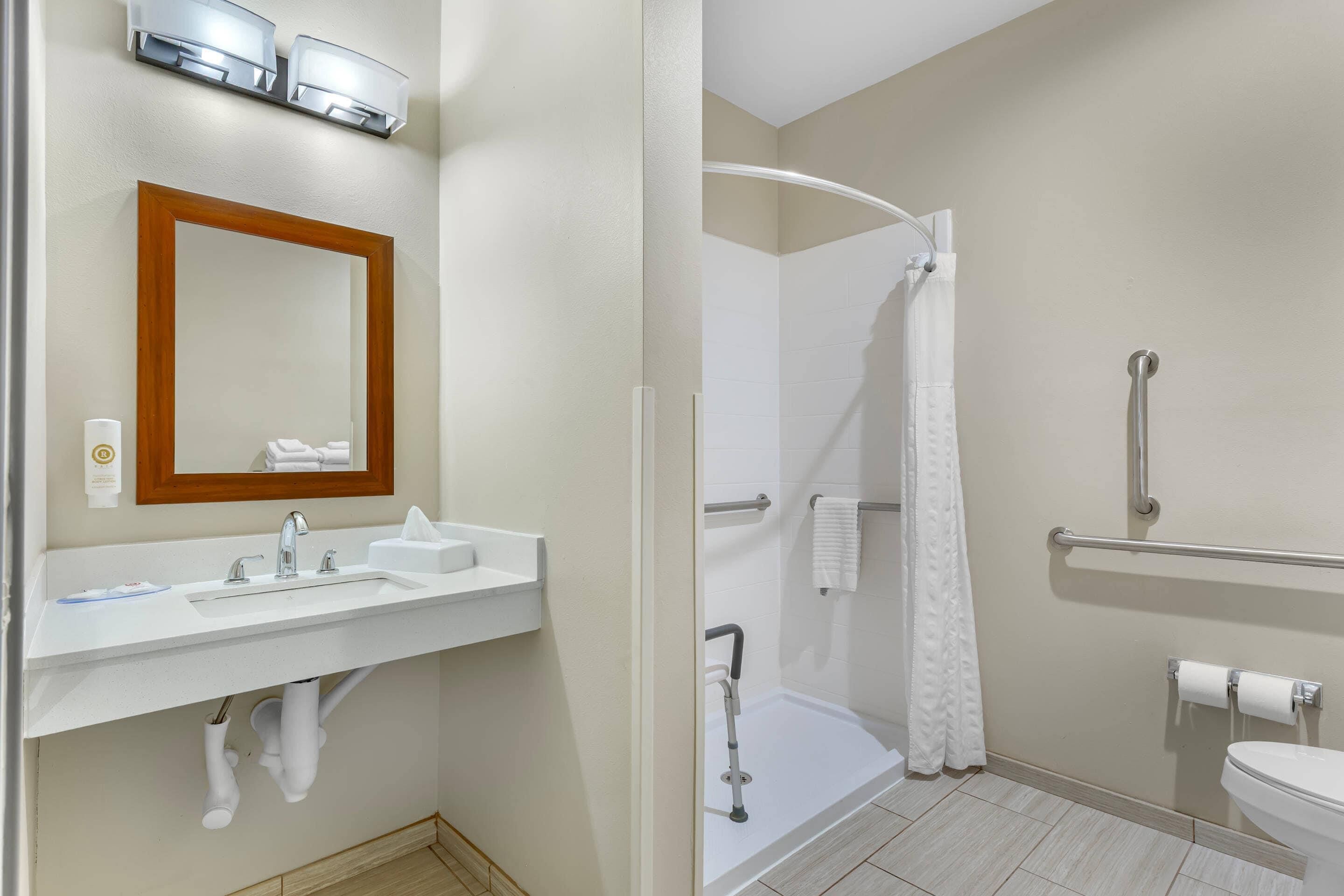 A bathroom with a sink, mirror, shower, and toilet.