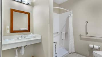 A bathroom with a sink, mirror, shower, and toilet.