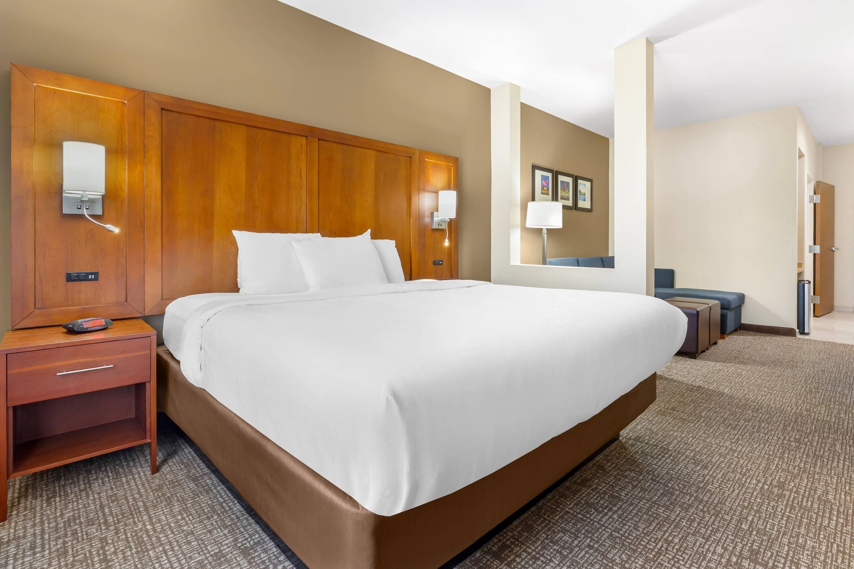 Ein Hotelzimmer mit einem großen Bett, Nachttischen, einem Schreibtisch und einem Sessel.