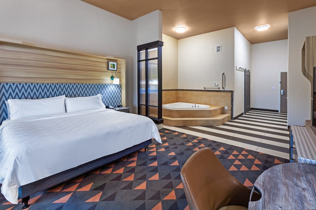 Ett hotellrum med en säng, ett badrum med badkar och en sittgrupp.