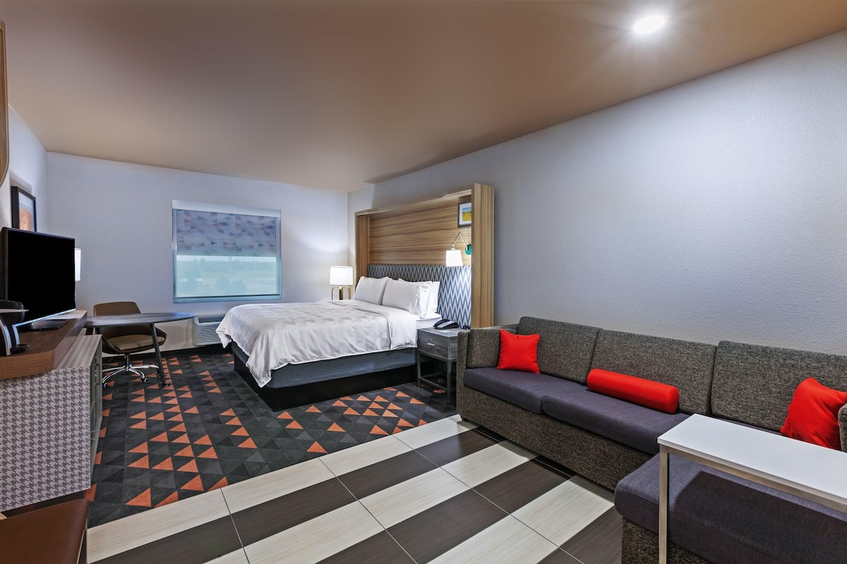 Ett hotellrum med en säng, en soffa, ett skrivbord och en tv.
