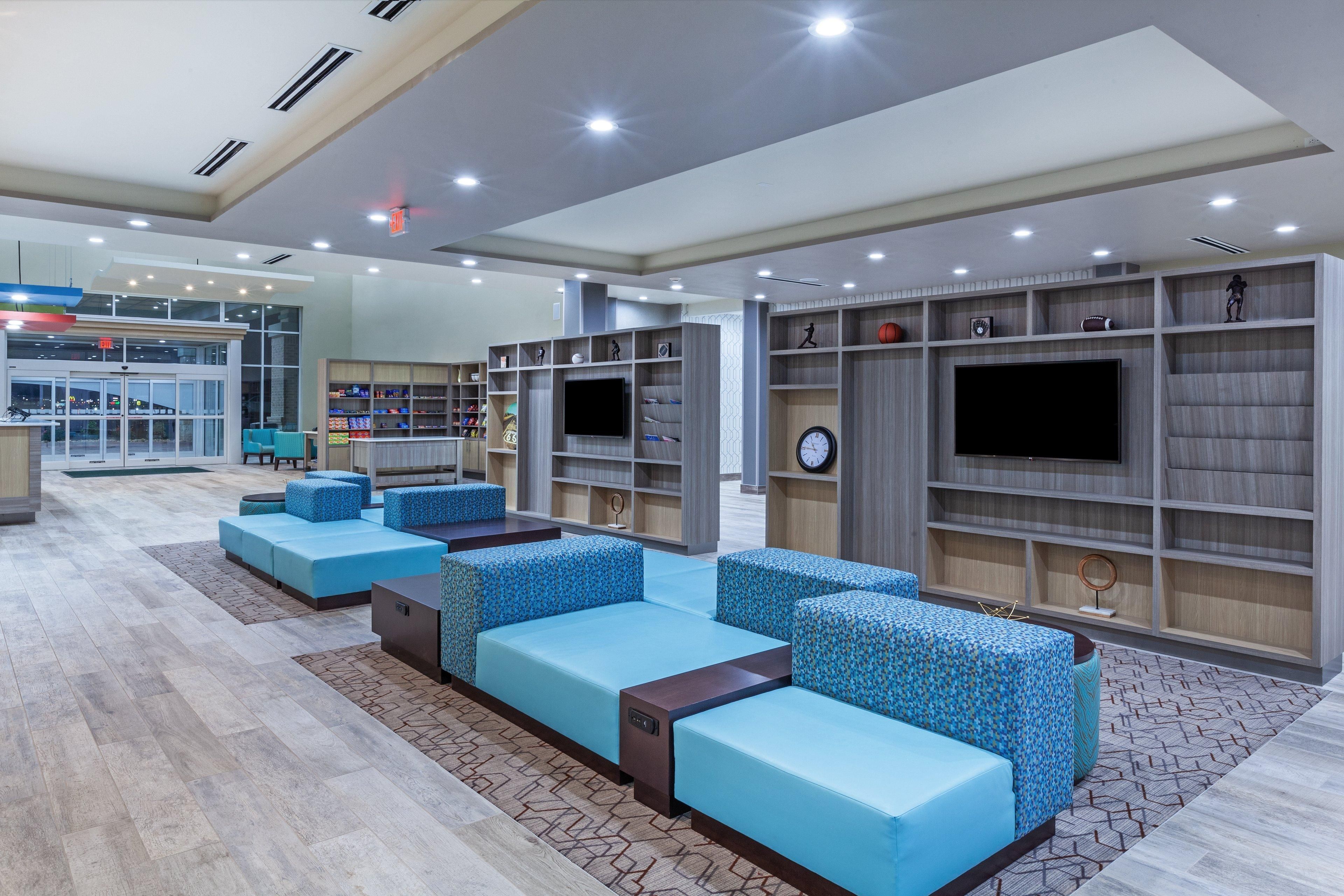 A modern lounge area with seating, a TV, and a bookshelf.