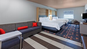 A hotel room with a sofa, two beds, a desk, and a TV. - Holiday Inn Amarillo East (Amarillo)