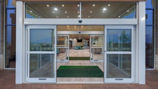 A modern building entrance with glass doors and a green mat. - Holiday Inn Amarillo East (Amarillo)