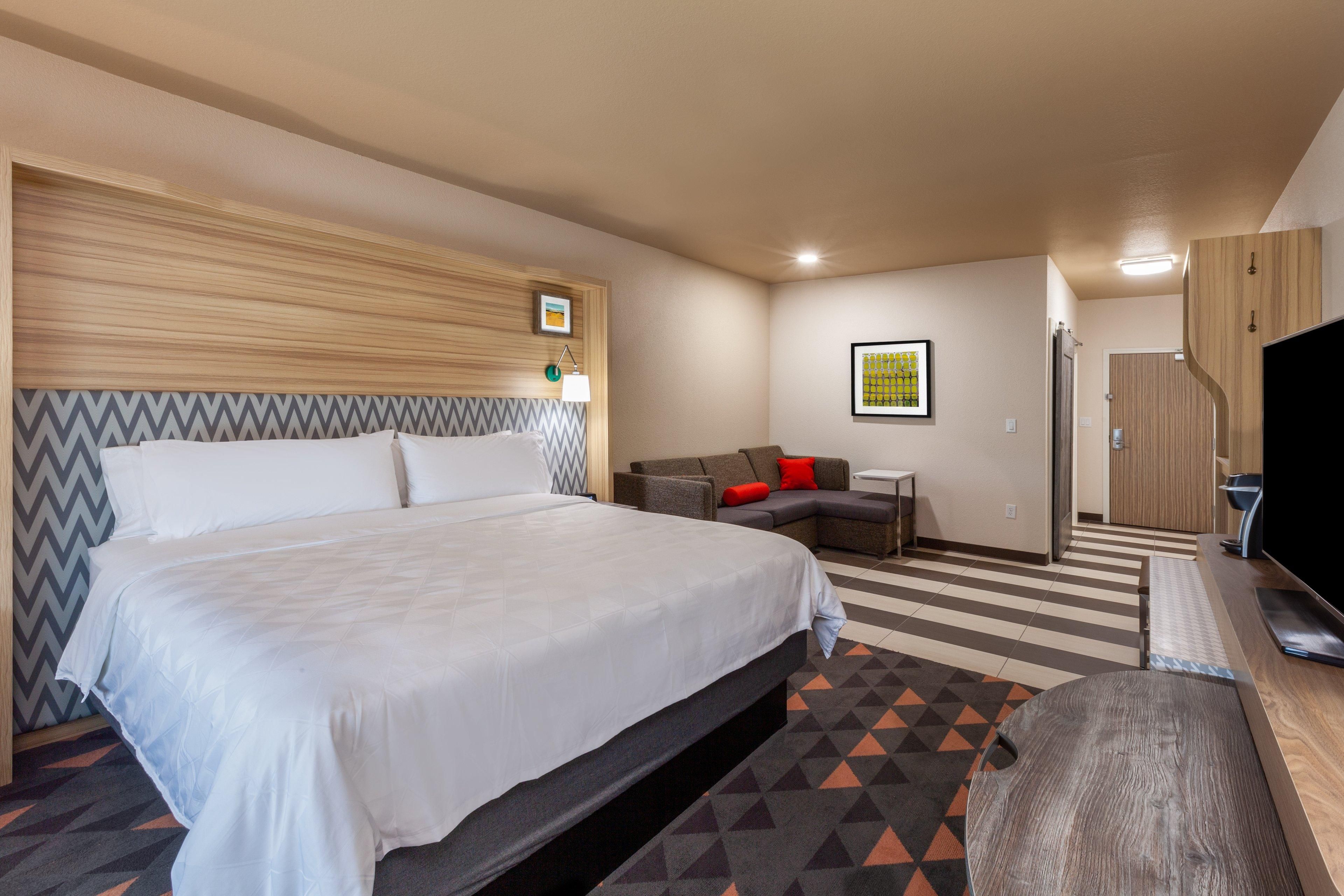 Una habitación de hotel con una cama grande, un sofá, un televisor y un escritorio.