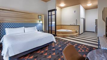 Ein Hotelzimmer mit einem Bett, einem Badezimmer mit Badewanne sowie einem kleinen Tisch und einem Stuhl.