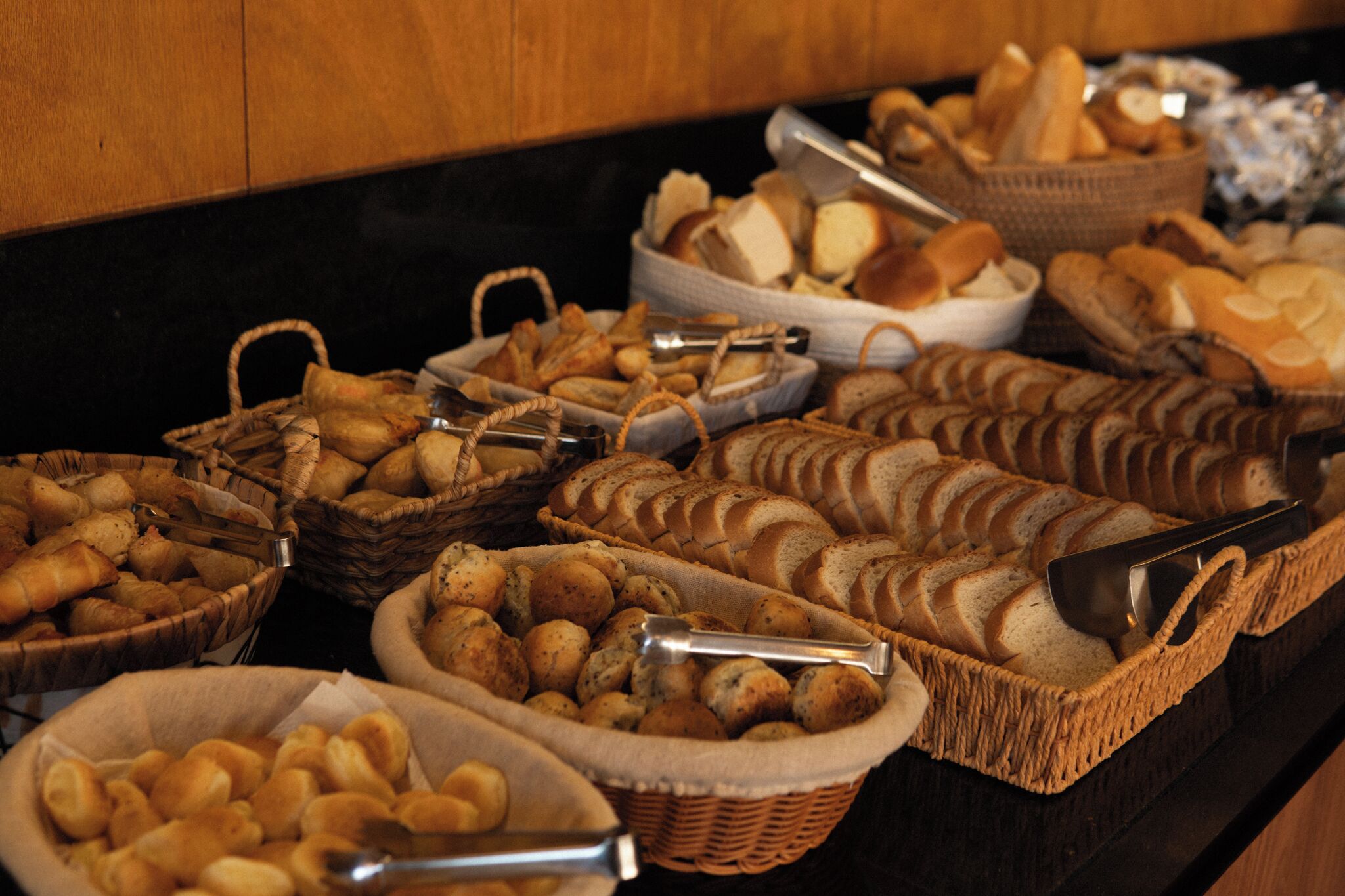 A buffet with various breads and pastries in baskets.