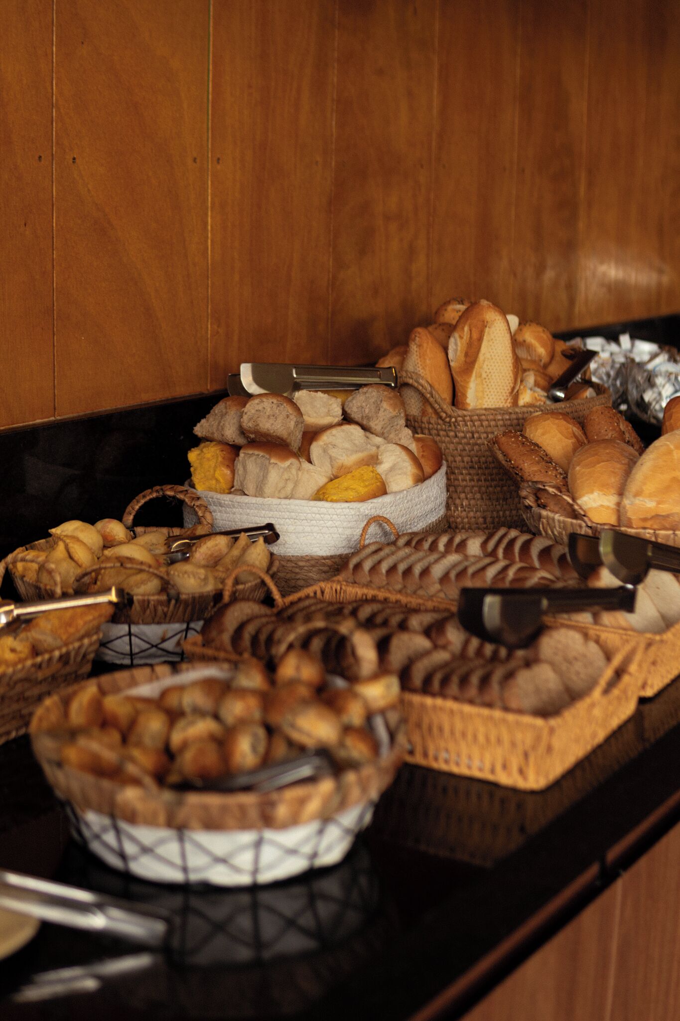 A buffet table with various breads and pastries.