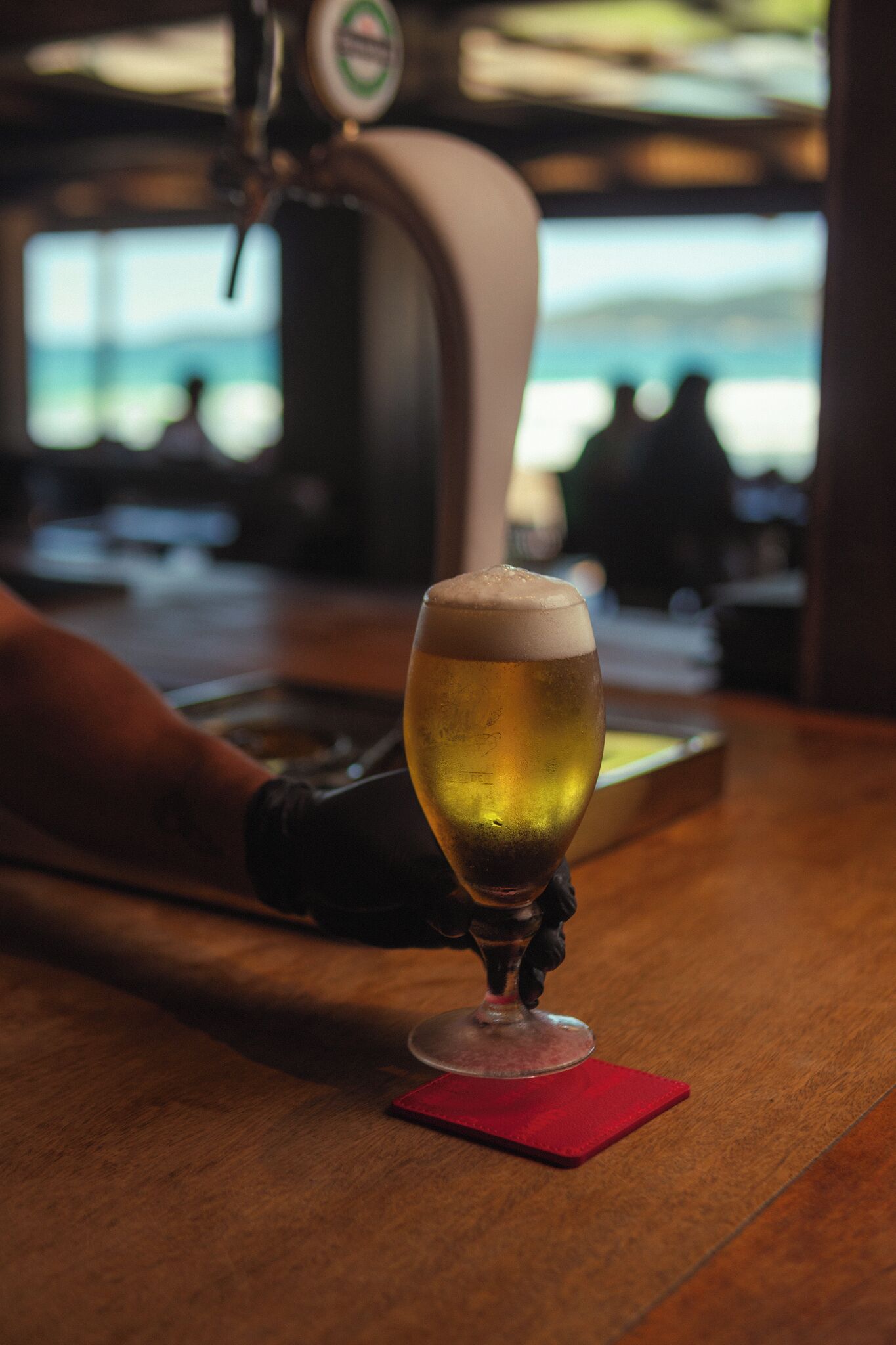 A glass of beer on a bar counter with a tap in the background.