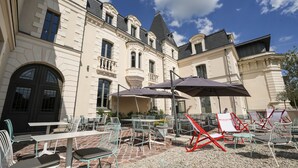 Une cour dotée d’un espace extérieur aménagé avec des tables, des chaises et des parasols.