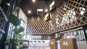 A modern reception area with a geometric wooden partition, a reception desk, and a bar area. - Hôtel Le Magic & Spa (Vitre)