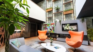 Un espace intérieur moderne comprenant un canapé, deux fauteuils orange, une table basse et un téléviseur.