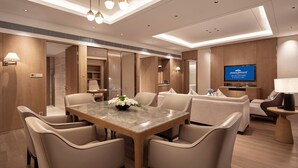Una habitación de hotel moderna con comedor, un sofá, televisor y escritorio.