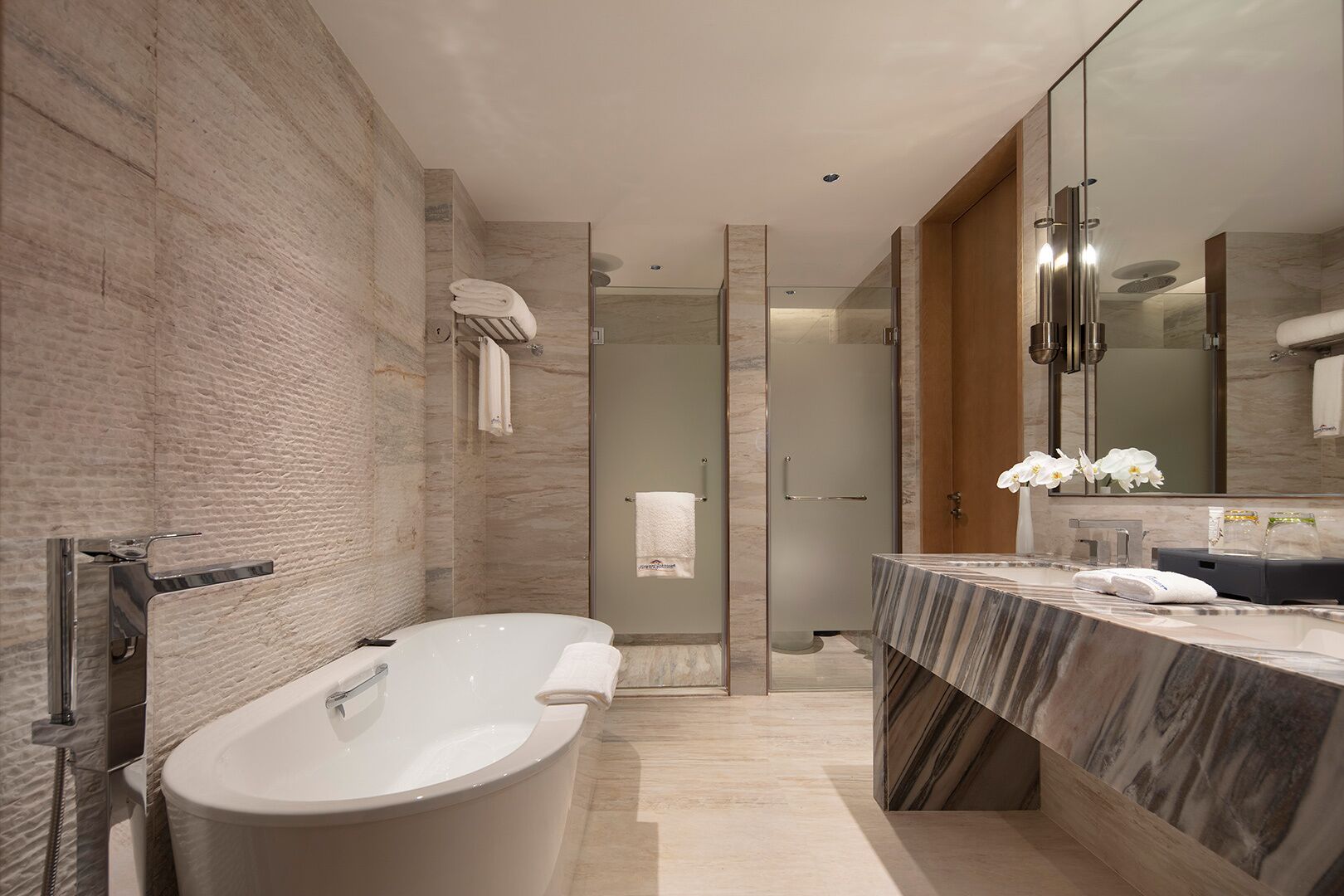 A modern bathroom with a freestanding bathtub, a large mirror, and a marble countertop.