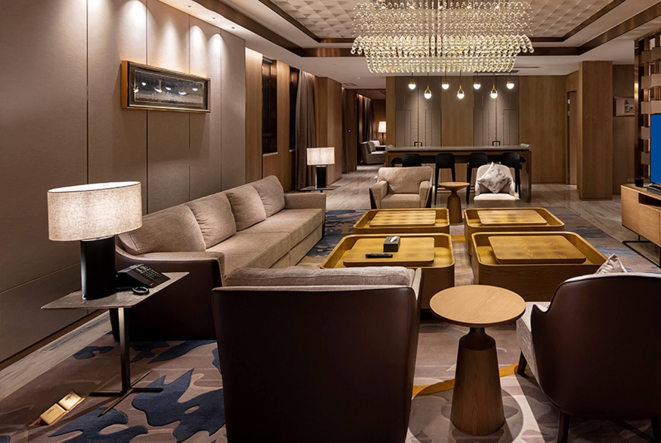 Una moderna hall dell'hotel con un divano, poltrone, un tavolino, una TV e un lampadario.