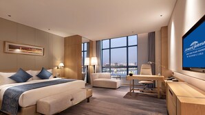 Una habitación de hotel con una cama grande, un escritorio, una silla y un televisor.