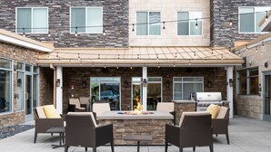 An outdoor patio with a stone fire table, wicker chairs, and a grill. - Residence Inn by Marriott Toledo West (Toledo)