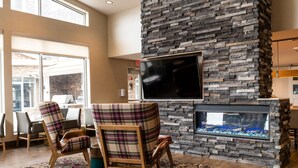 A modern living room with a stone fireplace, a flat-screen TV, and plaid chairs. - Residence Inn by Marriott Toledo West (Toledo)