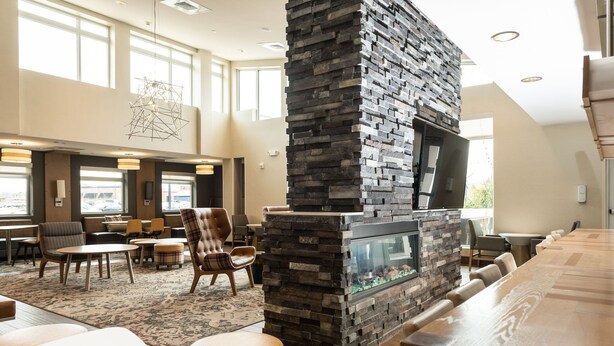 A spacious indoor area with a stone fireplace, comfortable seating, and large windows. - Residence Inn by Marriott Toledo West (Toledo)