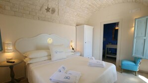 Ein Schlafzimmer mit einem großen Bett, einem Nachttisch, einer Lampe, einem Kleiderschrank und einem durchgegangenen Tür erkennbaren Badezimmer.