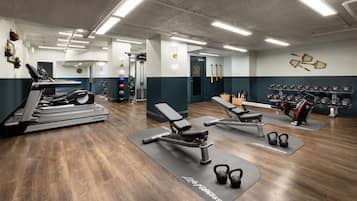 Un gimnasio con cintas de correr, bancos y máquinas de pesas.